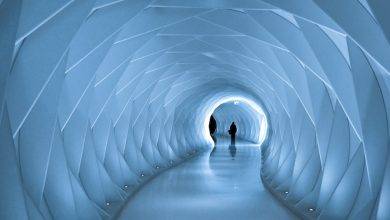 two people are walking through a tunnel in the snow